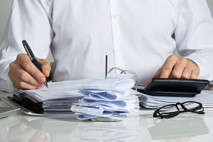 Midsection of businessman calculating invoice at office desk