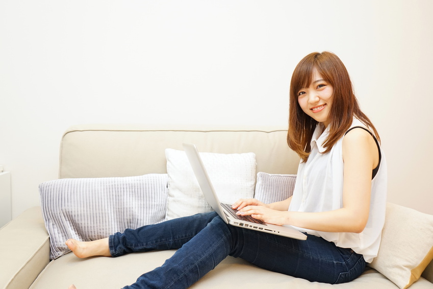 Young japanese woman using a computer on the sofa ソファーでリラックスしてパソコンを使う若い日本人の女性